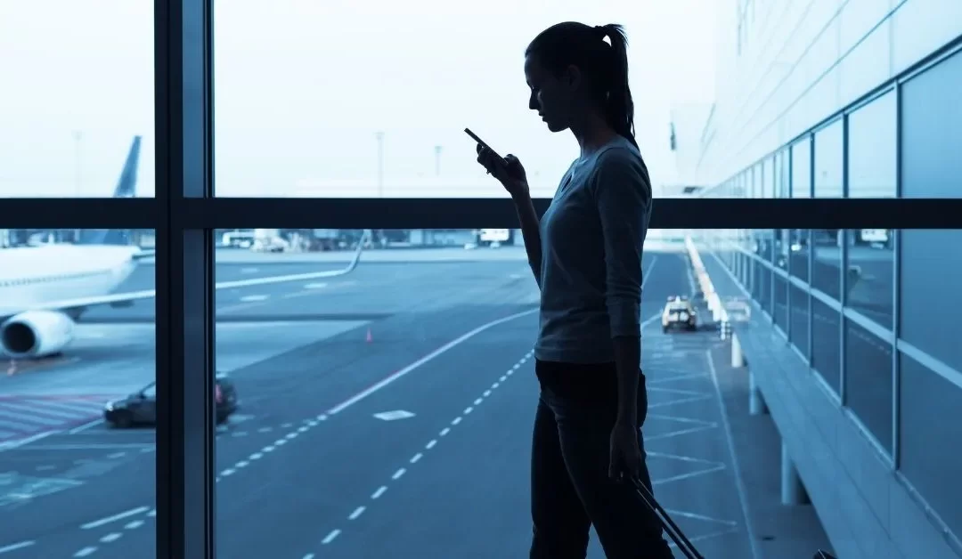 Femme avec un cellulaire a l'aéroport